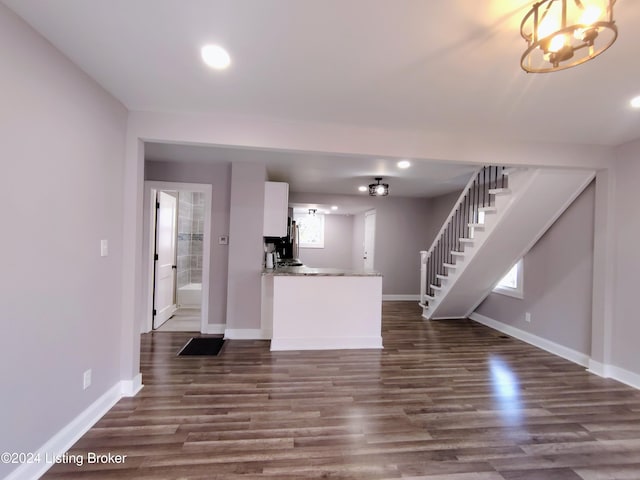 kitchen with white cabinetry, a notable chandelier, dark wood-type flooring, and kitchen peninsula