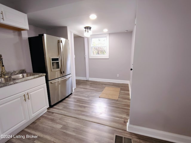 kitchen with white cabinetry, sink, light wood-type flooring, and stainless steel fridge with ice dispenser