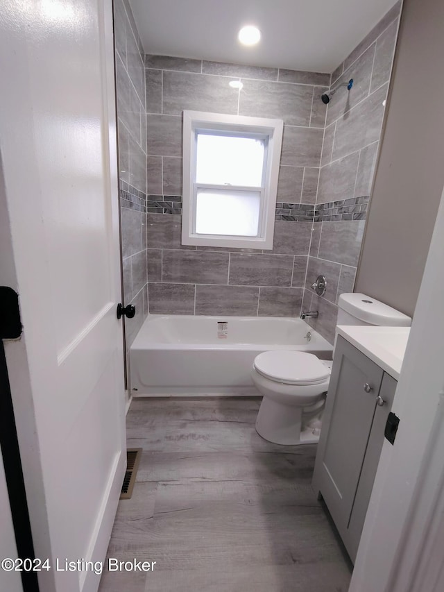 full bathroom with vanity, toilet, hardwood / wood-style flooring, and tiled shower / bath combo