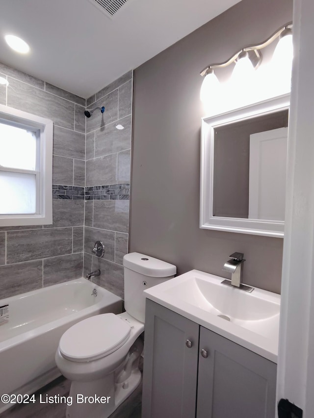 full bathroom with tiled shower / bath, vanity, and toilet