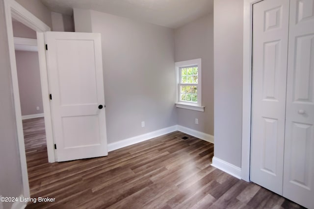 unfurnished bedroom with a closet and hardwood / wood-style flooring