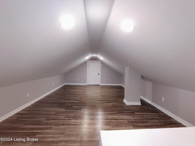 additional living space featuring dark wood-type flooring and vaulted ceiling