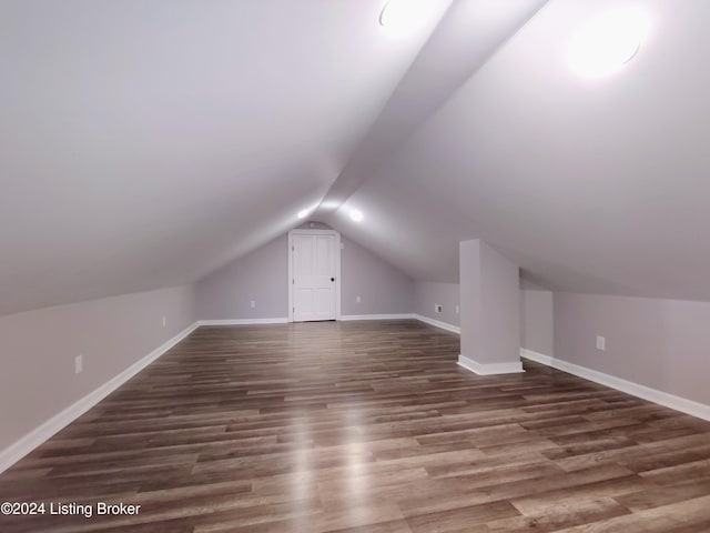 additional living space featuring lofted ceiling and dark hardwood / wood-style flooring