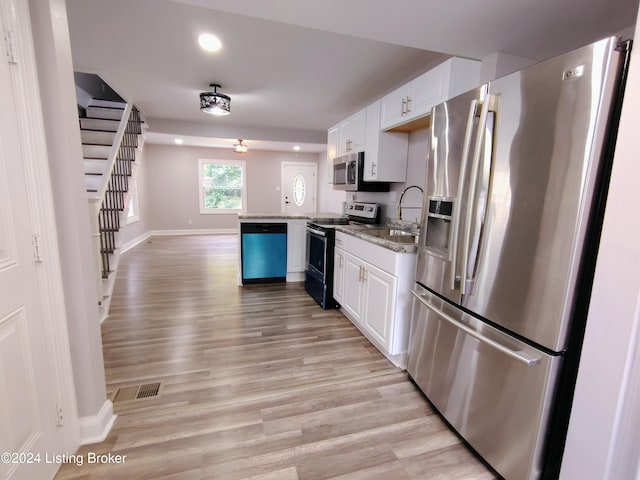 kitchen with kitchen peninsula, sink, white cabinets, appliances with stainless steel finishes, and light hardwood / wood-style floors