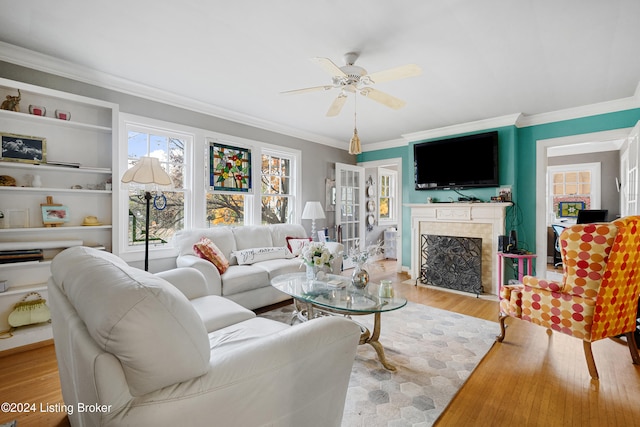 living room with ornamental molding, light hardwood / wood-style flooring, built in shelves, and ceiling fan