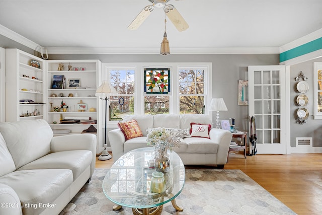 living room with crown molding, wood-type flooring, and ceiling fan