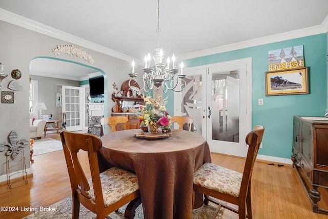 dining space with light hardwood / wood-style floors, a notable chandelier, ornamental molding, and plenty of natural light