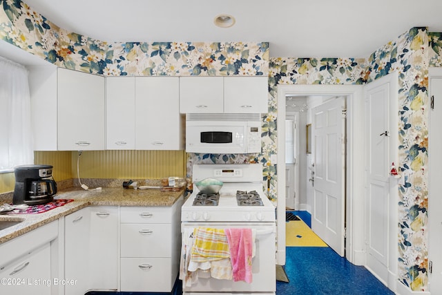 kitchen featuring white appliances, light stone countertops, and white cabinetry