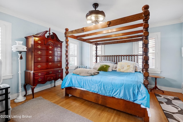 bedroom featuring crown molding, beam ceiling, and light wood-type flooring