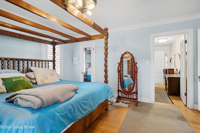 bedroom featuring crown molding, beamed ceiling, light hardwood / wood-style flooring, and ensuite bathroom