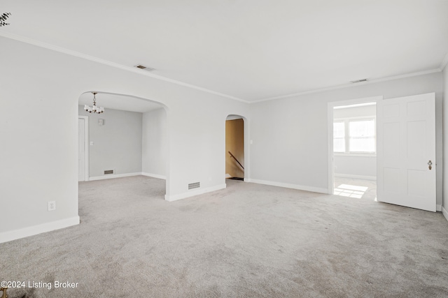 carpeted empty room featuring ornamental molding and a chandelier