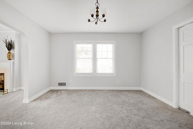 unfurnished room featuring a chandelier and light colored carpet