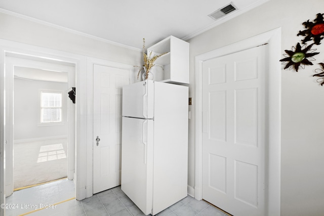 kitchen featuring ornamental molding, white refrigerator, and light colored carpet