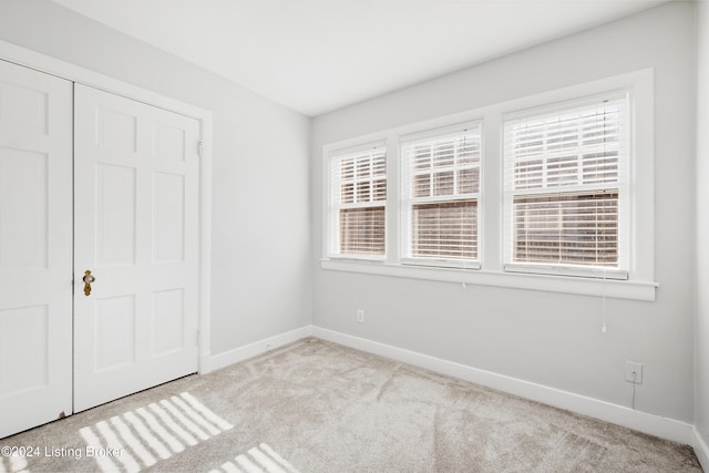 unfurnished bedroom featuring light colored carpet and a closet