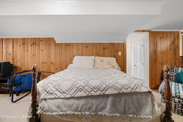 carpeted bedroom featuring wood walls and ornamental molding