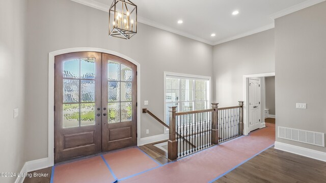 entrance foyer with crown molding, plenty of natural light, dark wood-type flooring, and french doors