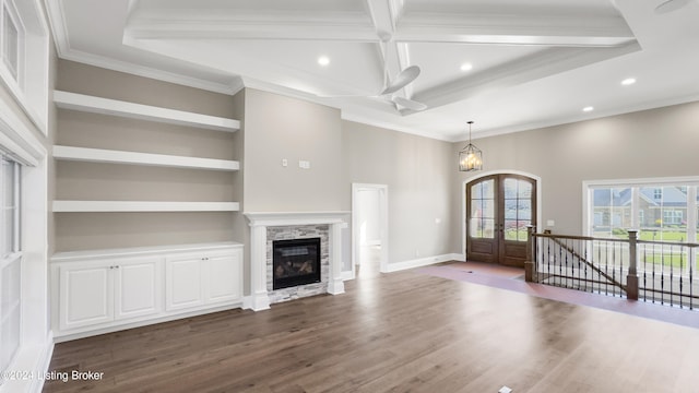 unfurnished living room with french doors, ornamental molding, wood-type flooring, a fireplace, and a chandelier