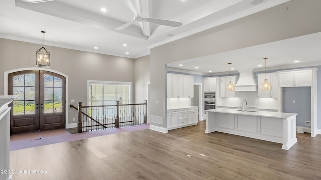 kitchen with wood-type flooring, premium range hood, and sink