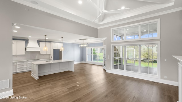 kitchen with a center island with sink, custom exhaust hood, white cabinets, and dark wood-type flooring