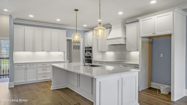 kitchen featuring hanging light fixtures, dark hardwood / wood-style flooring, white cabinetry, and a kitchen island with sink