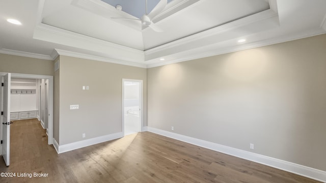 empty room featuring a tray ceiling, ceiling fan, wood-type flooring, and ornamental molding