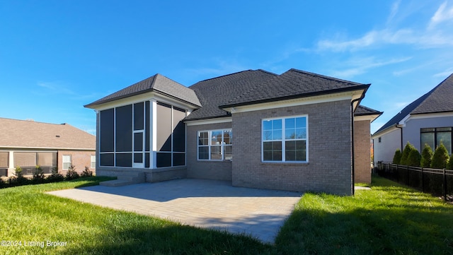 rear view of house featuring a patio, a lawn, and a sunroom