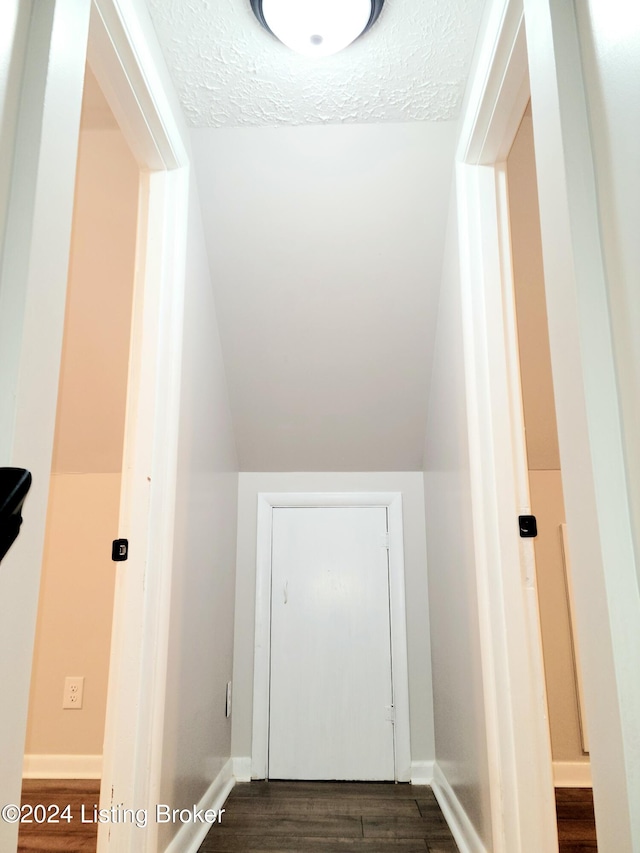 stairs with lofted ceiling, hardwood / wood-style floors, and a textured ceiling