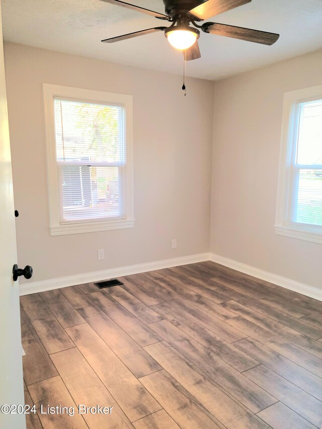 empty room with ceiling fan, wood-type flooring, and a wealth of natural light