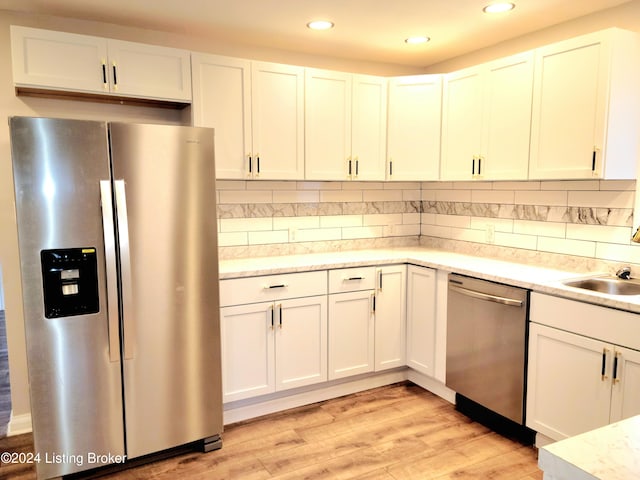 kitchen with white cabinetry, appliances with stainless steel finishes, light hardwood / wood-style flooring, and decorative backsplash