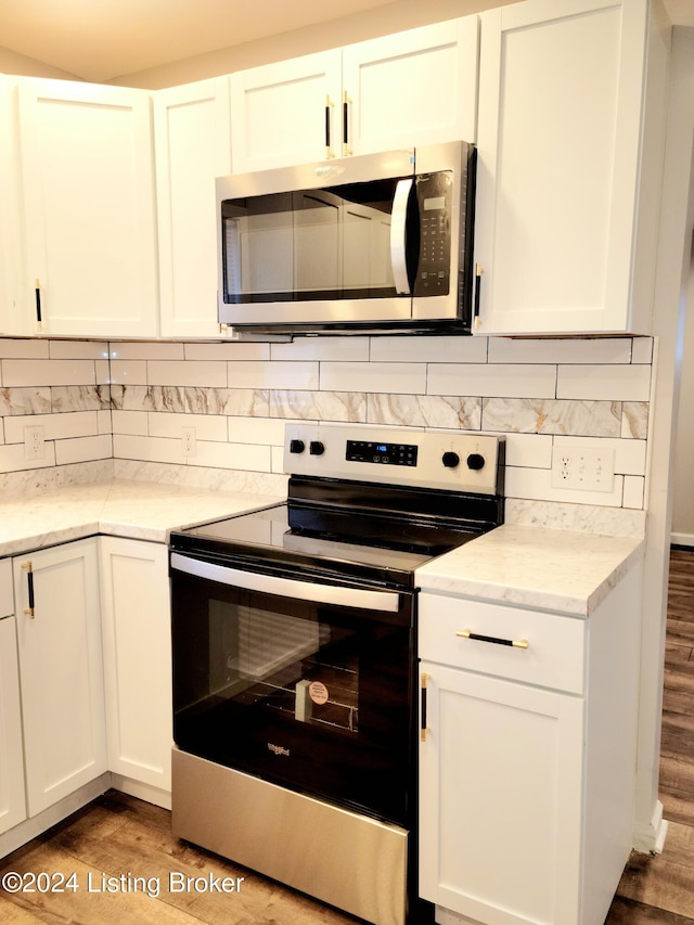 kitchen with backsplash, appliances with stainless steel finishes, light wood-type flooring, and white cabinets