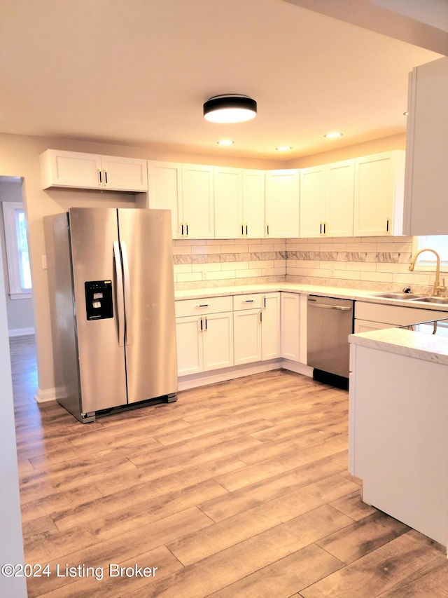 kitchen with appliances with stainless steel finishes, light hardwood / wood-style flooring, white cabinetry, and sink