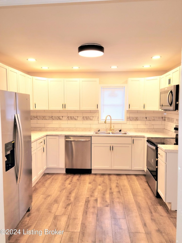 kitchen with light hardwood / wood-style floors, white cabinets, stainless steel appliances, and sink