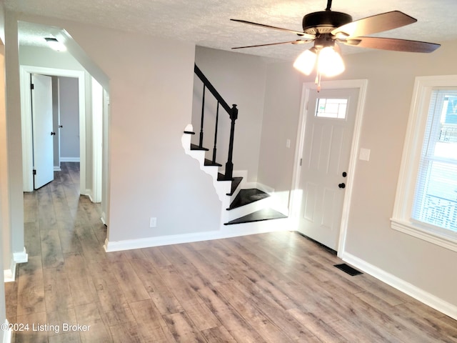 foyer with light hardwood / wood-style floors, a textured ceiling, and ceiling fan