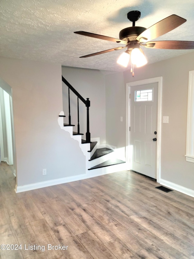 foyer featuring a textured ceiling, light wood-type flooring, and ceiling fan