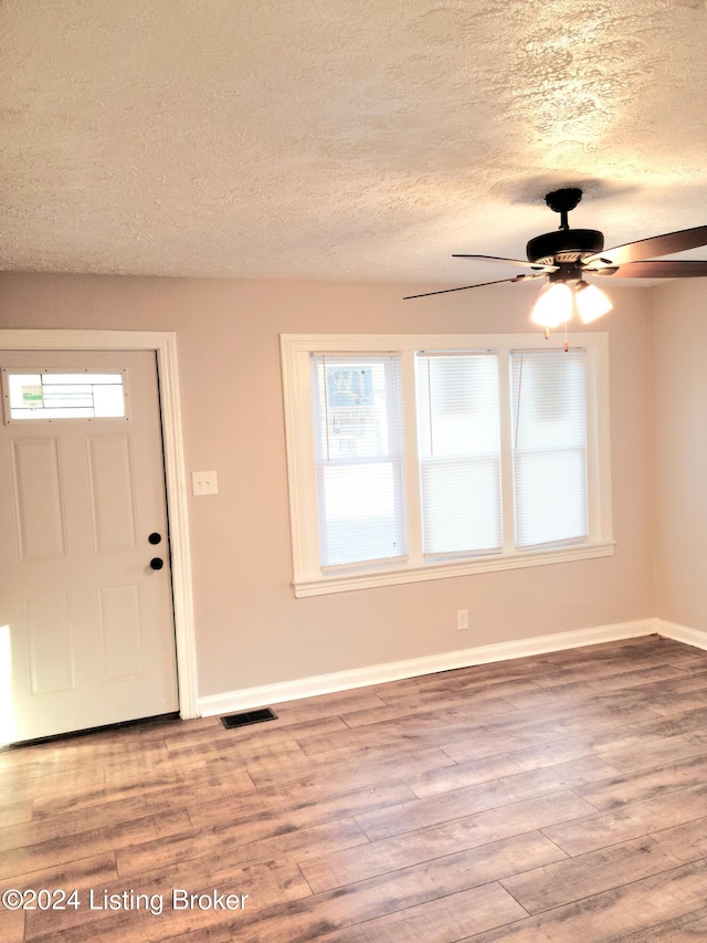 entryway with a textured ceiling, wood-type flooring, and a healthy amount of sunlight