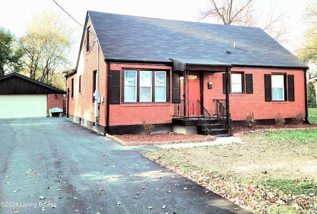 bungalow-style house featuring a garage and an outbuilding