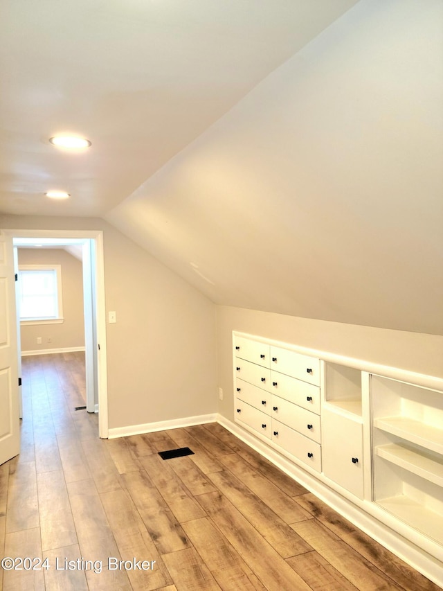 additional living space with vaulted ceiling and light wood-type flooring