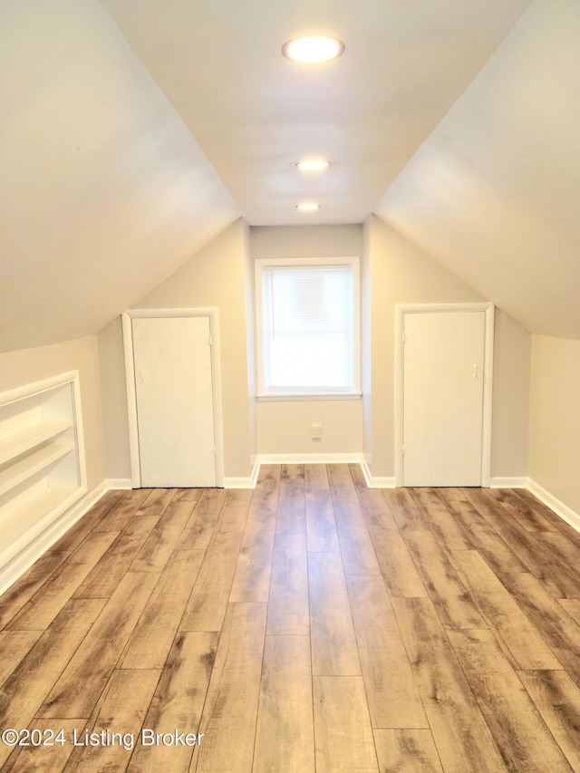 bonus room with light hardwood / wood-style floors, lofted ceiling, and built in features