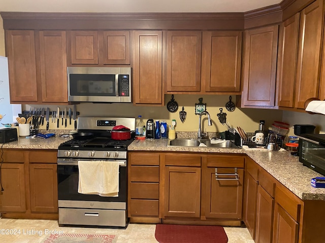 kitchen featuring sink, light stone counters, and appliances with stainless steel finishes