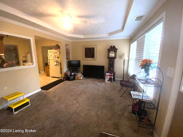 living room with a tray ceiling, carpet flooring, ceiling fan, and crown molding