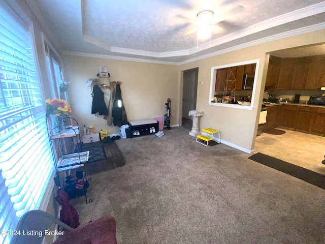 carpeted living room featuring ornamental molding, ceiling fan, and a raised ceiling