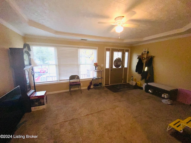 carpeted foyer entrance with ceiling fan, a textured ceiling, crown molding, and a tray ceiling