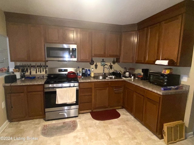 kitchen with appliances with stainless steel finishes, sink, and light stone counters