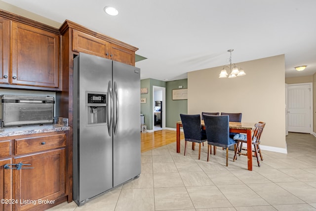 kitchen featuring stainless steel fridge with ice dispenser, decorative light fixtures, an inviting chandelier, and light tile patterned floors