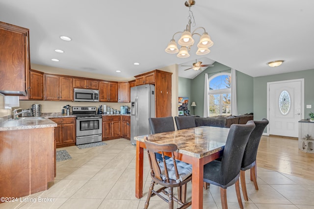 dining space featuring light tile patterned flooring, lofted ceiling, sink, and ceiling fan with notable chandelier