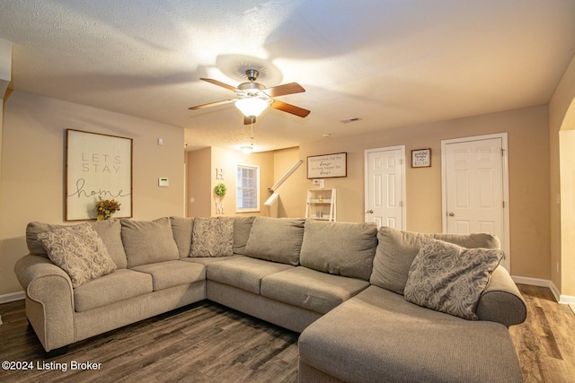 living room with a textured ceiling, dark hardwood / wood-style floors, and ceiling fan