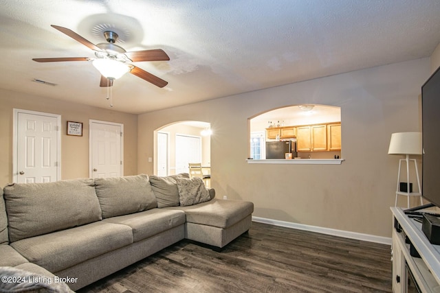 living room with dark wood-type flooring, a textured ceiling, and ceiling fan