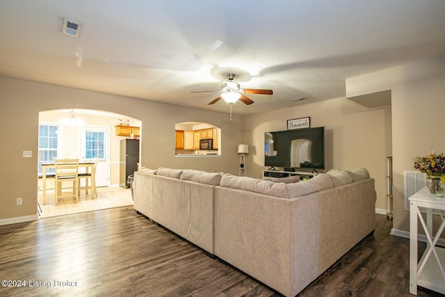 living room with dark wood-type flooring and ceiling fan with notable chandelier