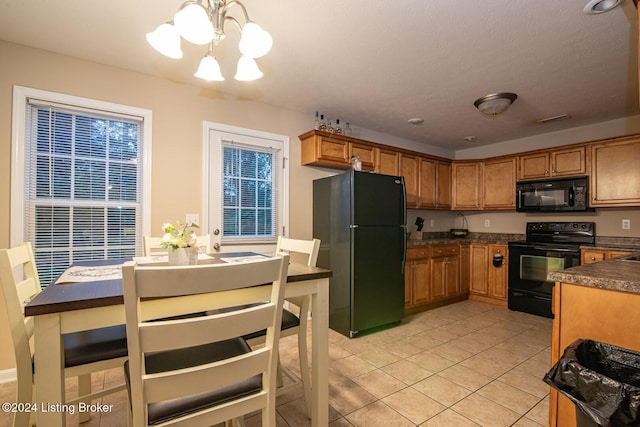 kitchen with hanging light fixtures, black appliances, light tile patterned floors, and a notable chandelier