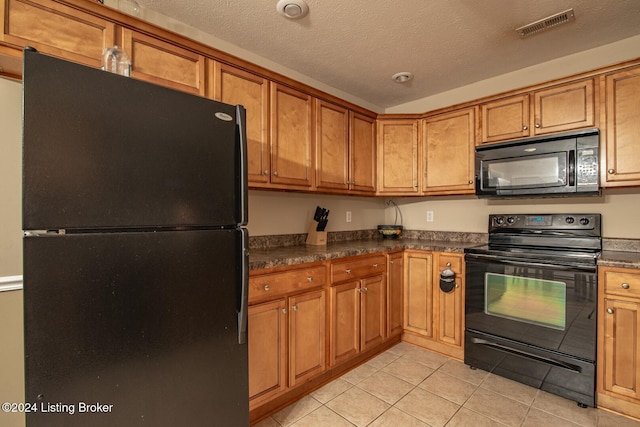 kitchen with a textured ceiling, light tile patterned floors, and black appliances